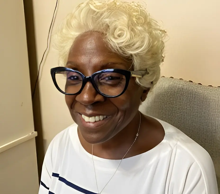 Smiling person with glasses and blonde hair.